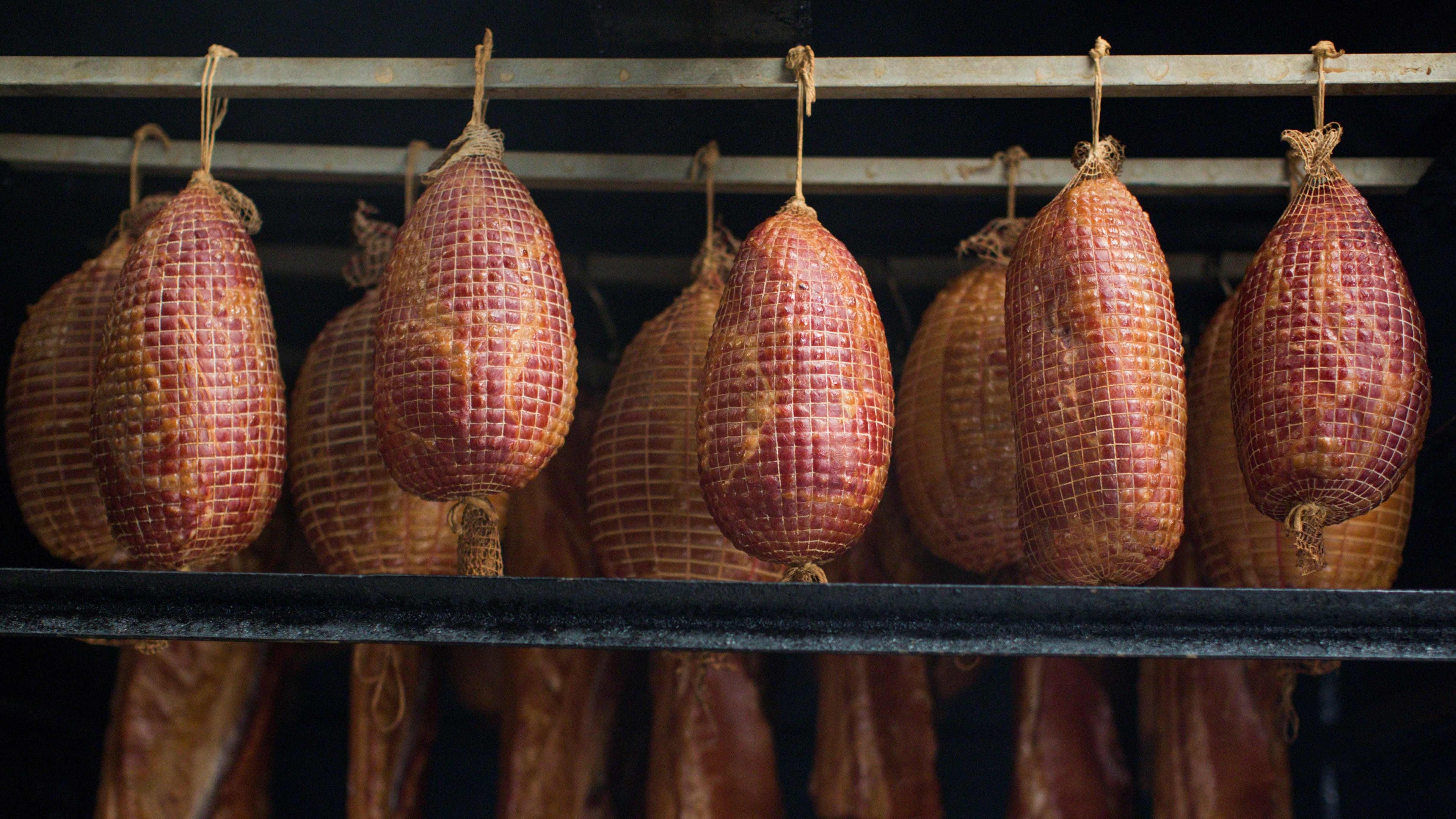 Hanging cured meats on a rack in a dark setting